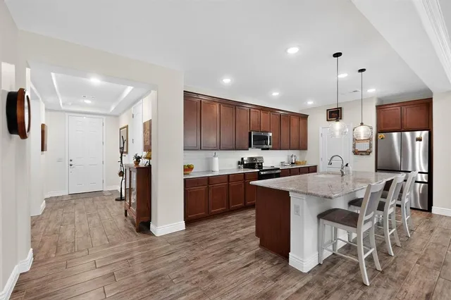 a kitchen with stainless steel appliances kitchen island granite countertop a refrigerator and a stove top oven