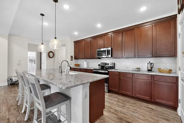 a kitchen with kitchen island granite countertop a sink counter top space appliances and cabinets