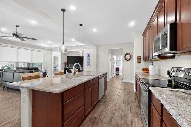 a kitchen with stainless steel appliances granite countertop a sink a stove and a wooden floors