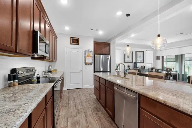 a kitchen with stainless steel appliances granite countertop sink stove refrigerator and cabinets