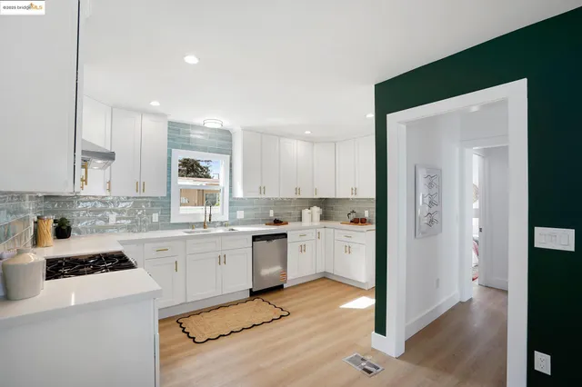 a kitchen with a sink a stove a refrigerator and white cabinets