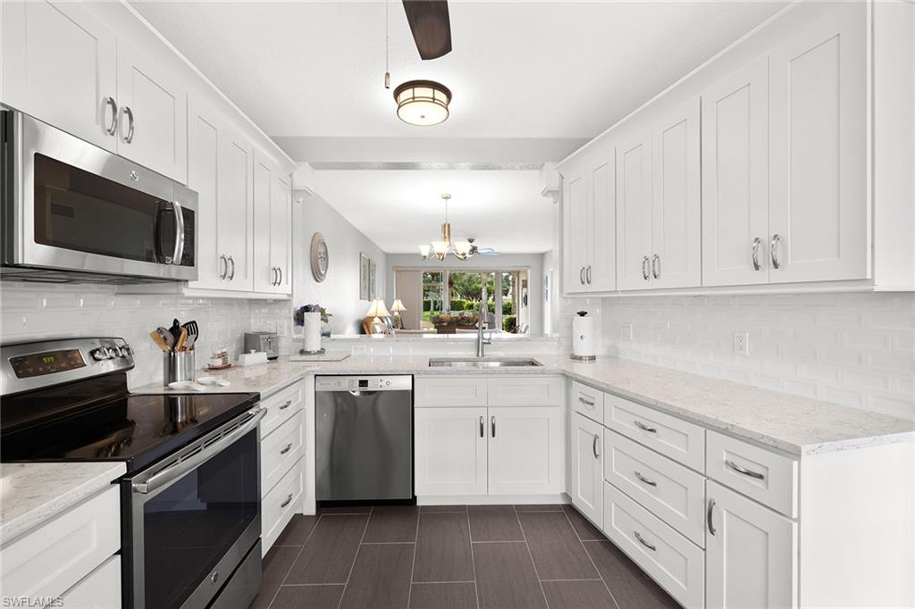 9022 Michael Circle, Unit 3 Naples, FL 34113 - Photo 11 of 25 a kitchen with white cabinets appliances a sink and a window