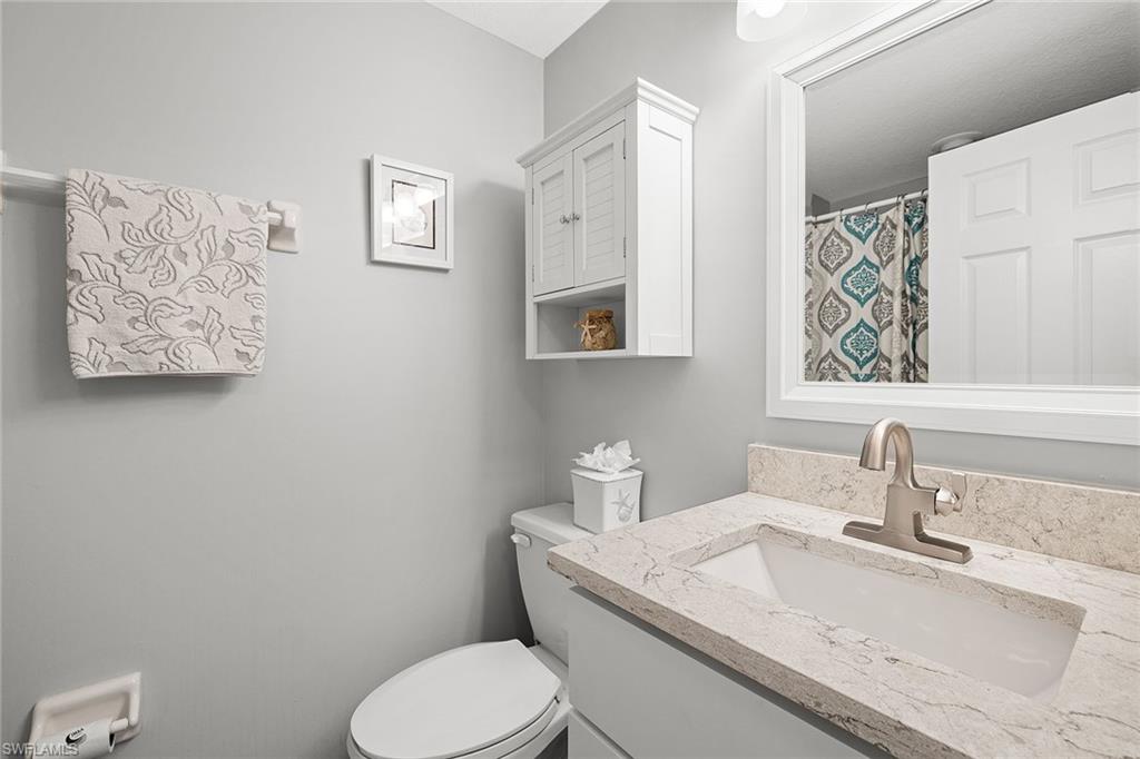 9022 Michael Circle, Unit 3 Naples, FL 34113 - Photo 20 of 25 a bathroom with a granite countertop toilet sink and mirror