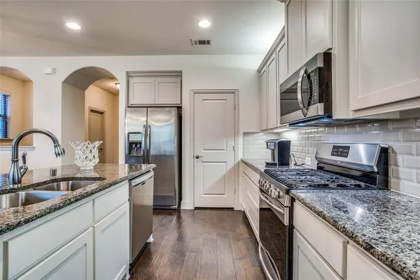 a kitchen with stainless steel appliances granite countertop a sink stove and refrigerator