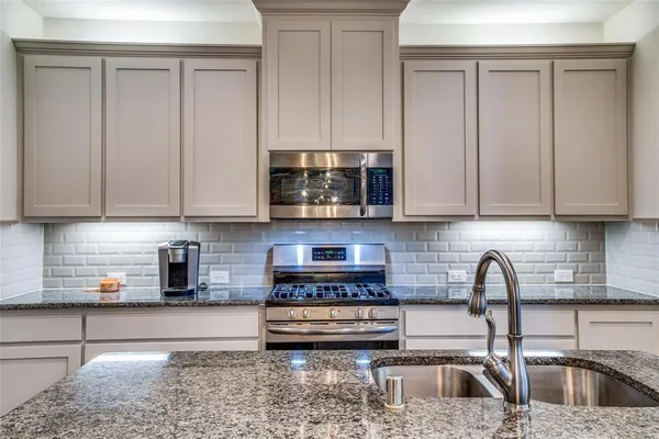 a kitchen with stainless steel appliances granite countertop a sink a stove and a white cabinets