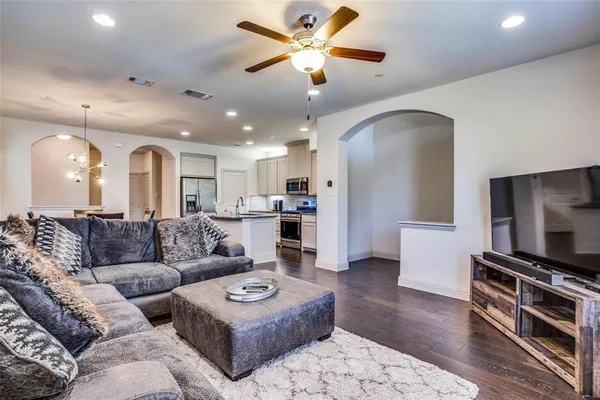 a living room with furniture kitchen view and a wooden floor