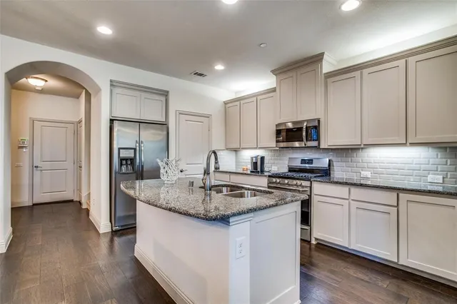 a kitchen with stainless steel appliances granite countertop a sink stove microwave and refrigerator