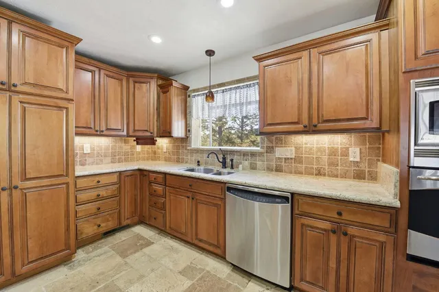 a kitchen with stainless steel appliances granite countertop a sink a stove and cabinets