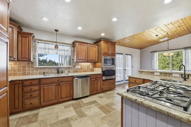 a large kitchen with stainless steel appliances granite countertop a stove top oven a sink dishwasher and cabinets with wooden floor