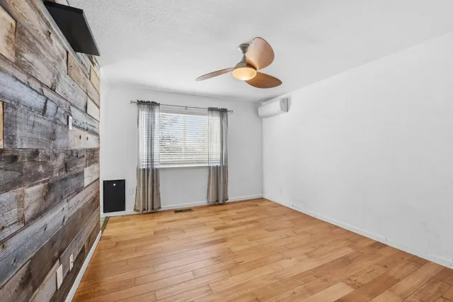 a view of empty room with wooden floor and fan