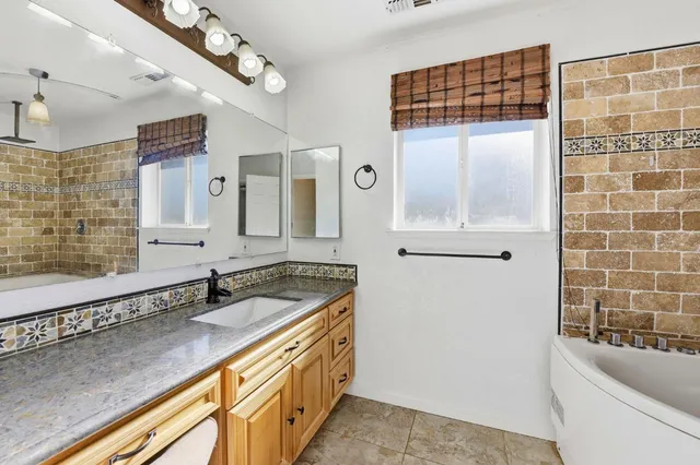 a bathroom with a granite countertop sink a bathtub a mirror and shower