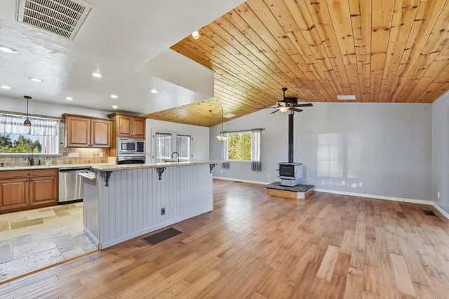 a kitchen with stainless steel appliances wooden floor and large windows