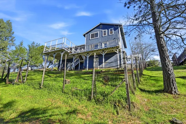 a view of a house with a big yard plants and large trees