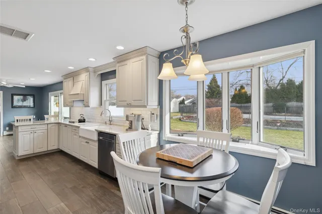 a kitchen with a stove a sink dishwasher a dining table and chairs with wooden floor