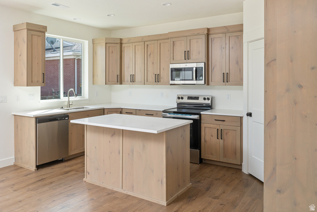 612 North 400 West Logan, UT 84321 - Photo 15 of 27 Kitchen featuring light wood-finish cabinetry, stainless steel appliances, a center island with white countertop, and wood-finish flooring
