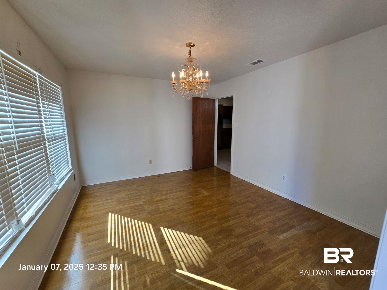 154 Byrd Road Monroeville, AL 36460 - Photo 14 of 26 Empty room with wood-type flooring and an inviting chandelier