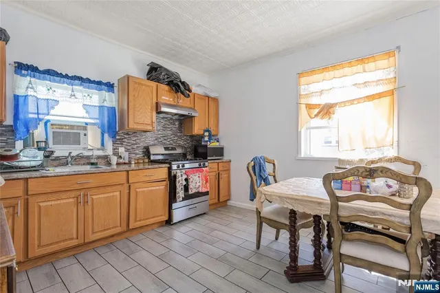 a kitchen with stainless steel appliances granite countertop a table chairs sink and cabinets