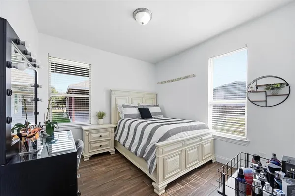 a bedroom with a bed and a large window with wooden floor