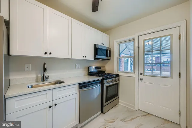 a kitchen with granite countertop a sink a stove and cabinets