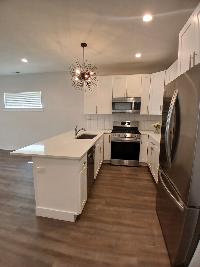 4608 South Indiana Avenue, Unit 1 Chicago, IL 60653 - Photo 8 of 24 a kitchen with granite countertop a refrigerator stove and sink
