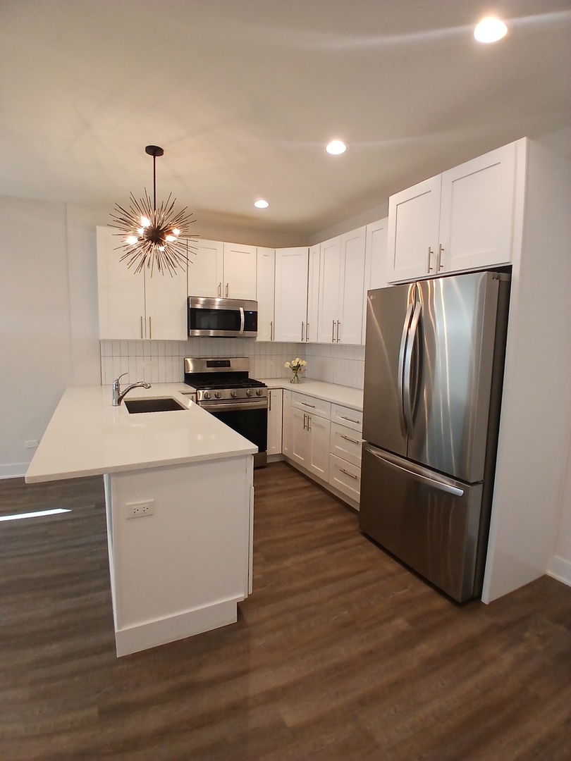 4608 South Indiana Avenue, Unit 1 Chicago, IL 60653 - Photo 9 of 24 a kitchen with kitchen island a sink cabinets and stainless steel appliances