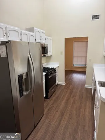 a kitchen with stainless steel appliances a refrigerator a stove and wooden floor