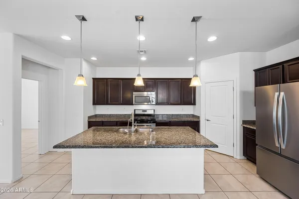 a large kitchen with stainless steel appliances kitchen island granite countertop a refrigerator a oven and a sink