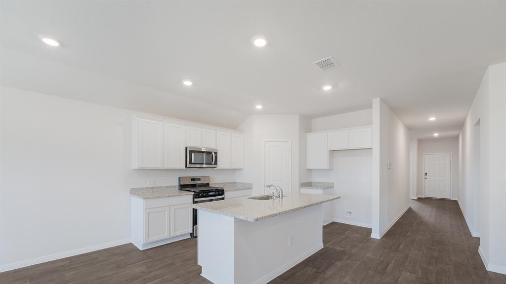 14021 Feinstein Street Manor, TX 78653 - Photo 8 of 25 A contemporary kitchen space boasts abundant storage, a spacious island, and elegant granite countertops.