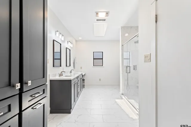 a view of a bathroom with sink shower and mirror