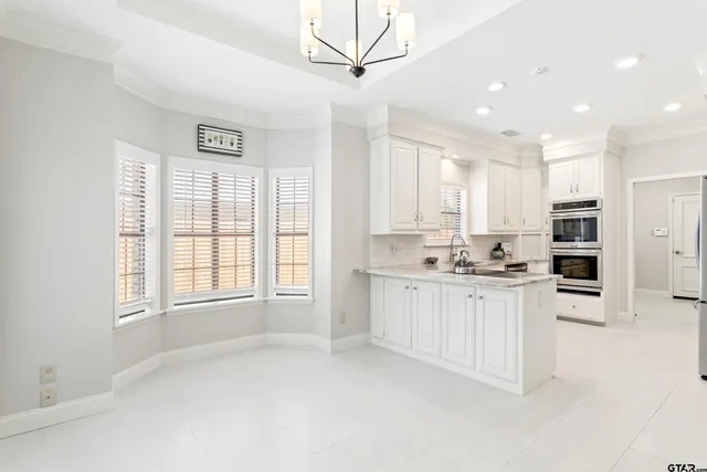 a kitchen with stainless steel appliances granite countertop a stove a sink and a refrigerator with white cabinets