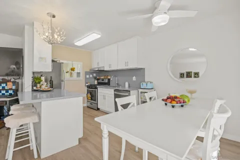 a kitchen with stainless steel appliances granite countertop a refrigerator a sink dishwasher a dining table and chairs with wooden floor