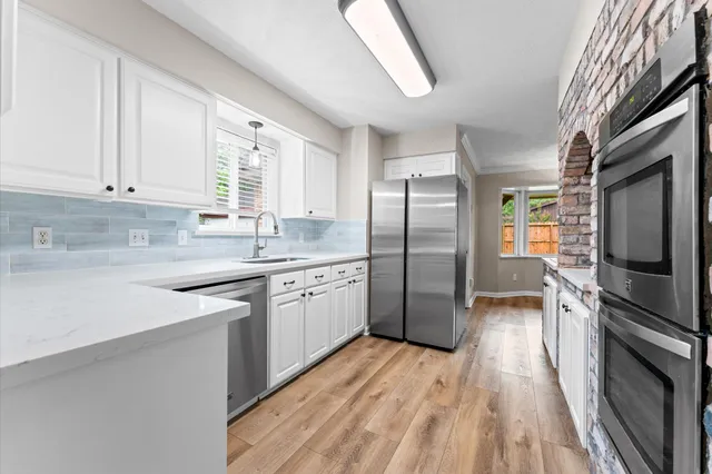 a kitchen with stainless steel appliances granite countertop a refrigerator a sink dishwasher a stove with wooden cabinets and floor