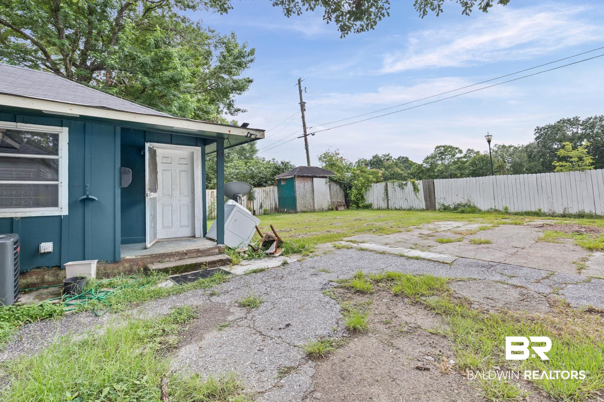 160 Glenn Avenue Mobile, AL 36606 - Photo 13 of 15 The property features a blue exterior, a covered porch entry, a paved area, and a white privacy fence