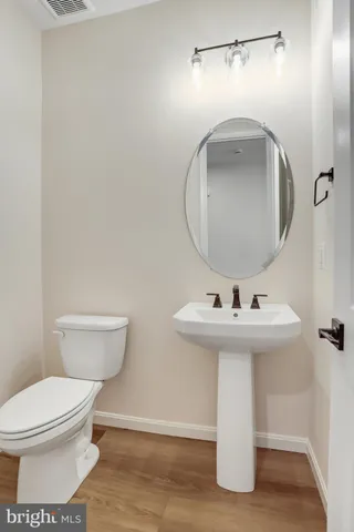 a view of an empty room with wooden floor and a kitchen