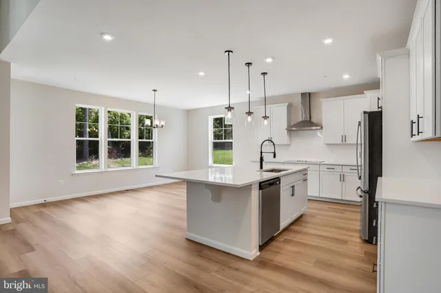 a kitchen with stainless steel appliances granite countertop a stove a sink a center island and a wooden floor