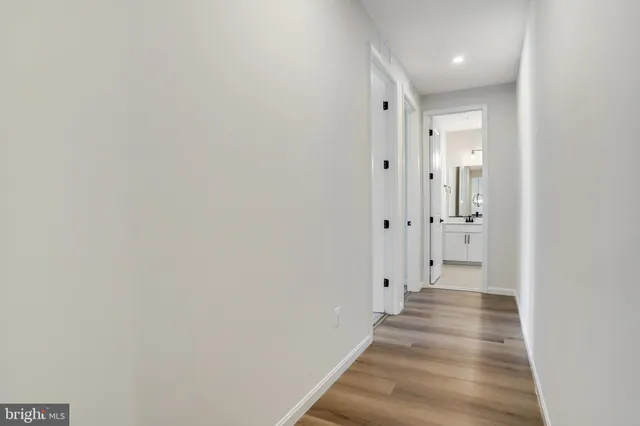 a view of a hallway with wooden floor and a bathroom