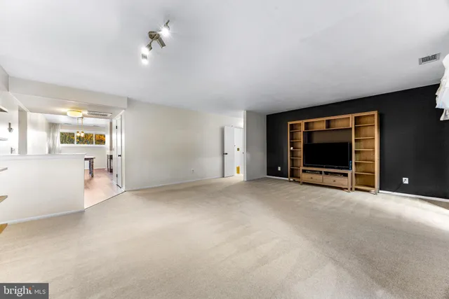 a view of an empty room with kitchen and a window