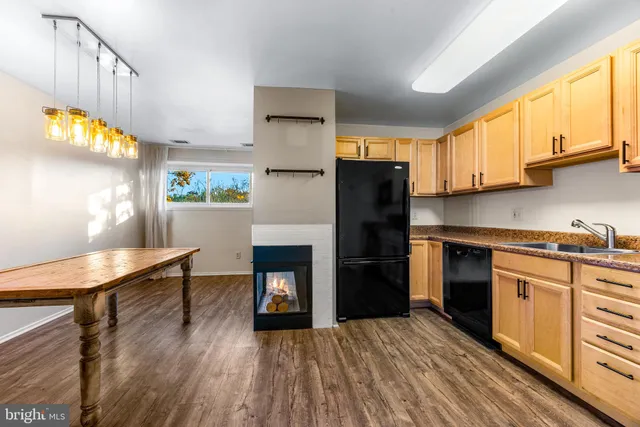 a kitchen with granite countertop a refrigerator a stove a sink dishwasher and wooden cabinets with wooden floor