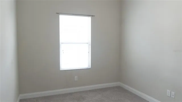 a view of an empty room with closet and a window