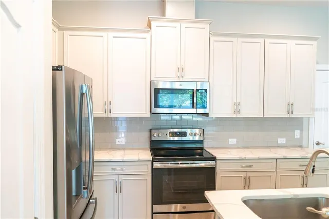 a kitchen with stainless steel appliances granite countertop a sink a stove a microwave and refrigerator
