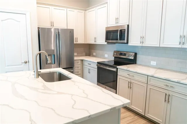 a kitchen with a sink a refrigerator and wooden floor