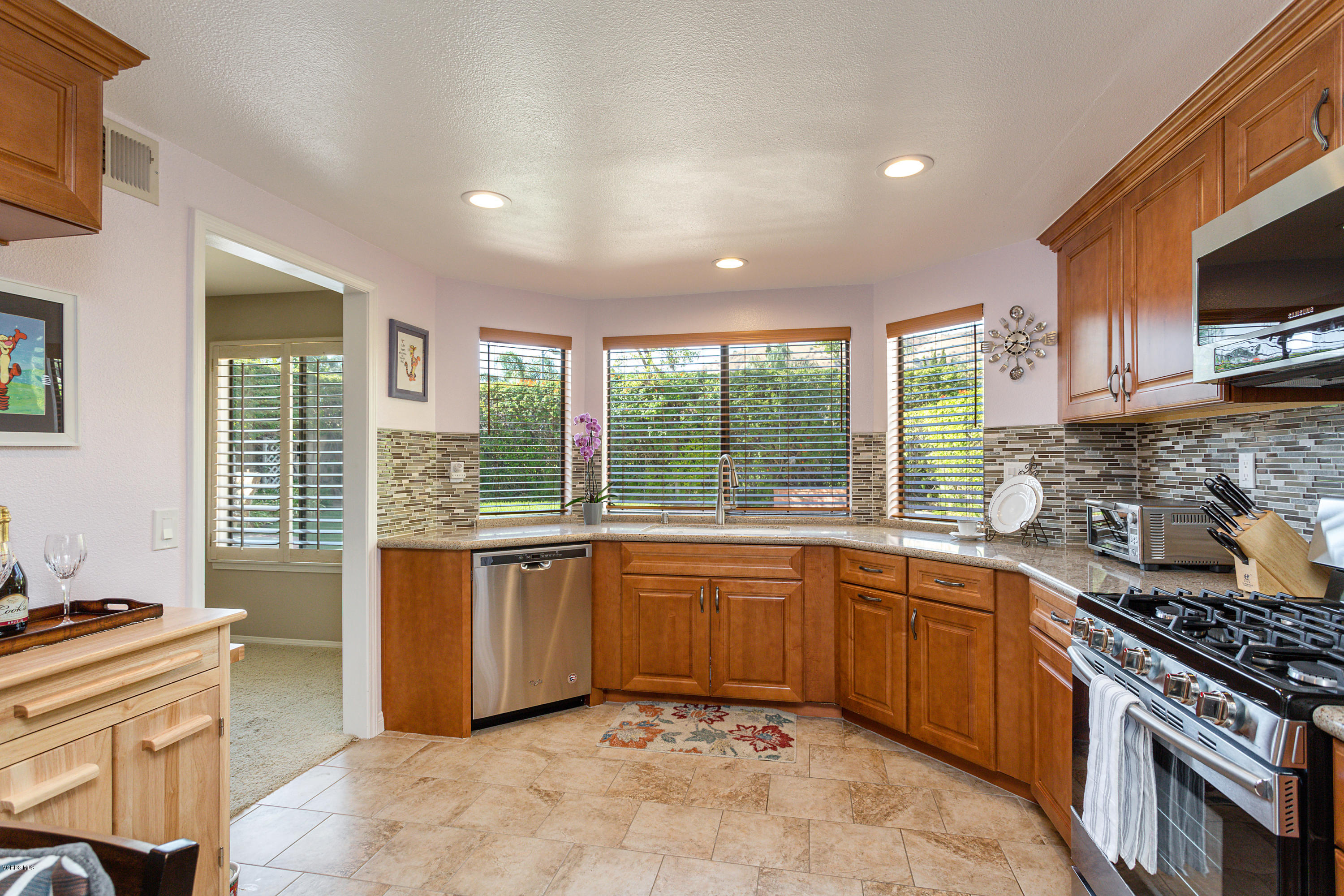 19641 Turtle Springs Way Porter Ranch, CA 91326 - Photo 11 of 31 a kitchen with stainless steel appliances granite countertop a stove top oven a sink dishwasher a dining table and chairs with wooden floor
