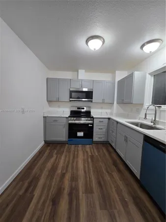 a kitchen with granite countertop a sink cabinets and stainless steel appliances