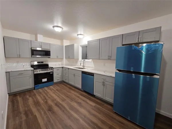 a kitchen with a refrigerator a oven and a sink