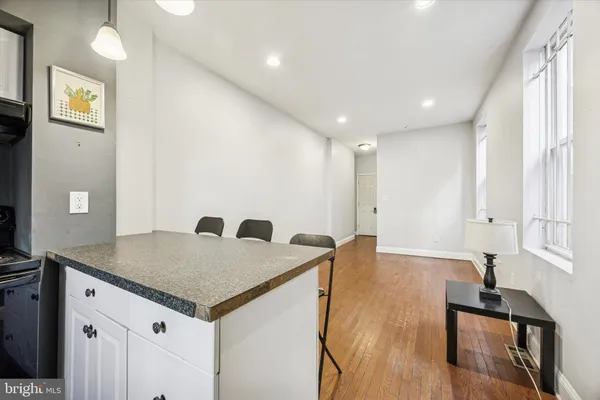 a view of kitchen island a sink wooden floor and entryway