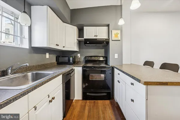a kitchen with granite countertop a sink dishwasher stove and cabinets