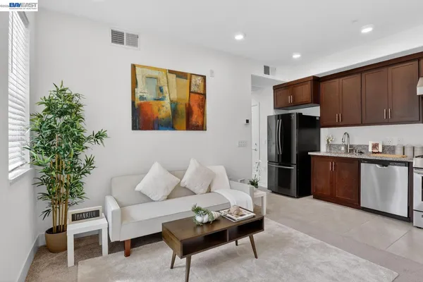 a living room with stainless steel appliances kitchen island furniture and a potted plant