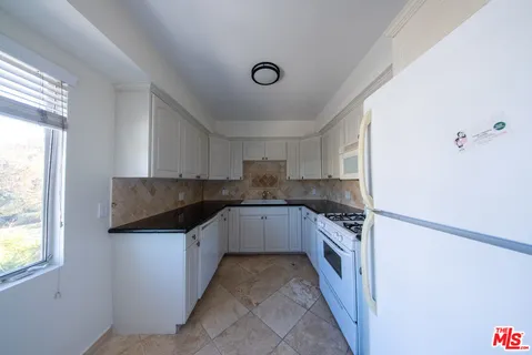 a kitchen with granite countertop a sink and white cabinets