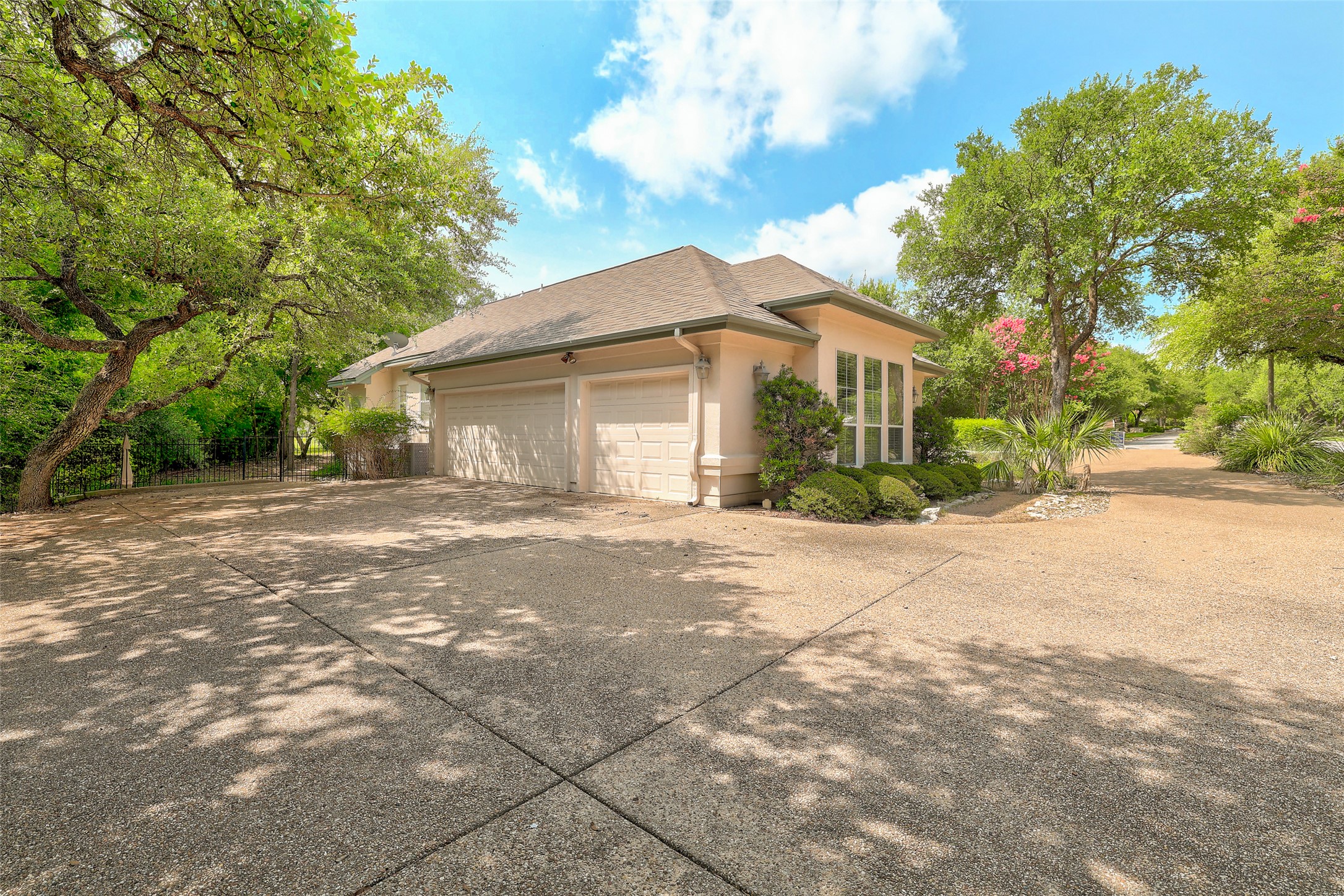 33 Meadows End Georgetown, TX 78628 - Photo 3 of 40 A well-maintained concrete driveway leads to a charming home nestled among mature trees and vibrant greenery.