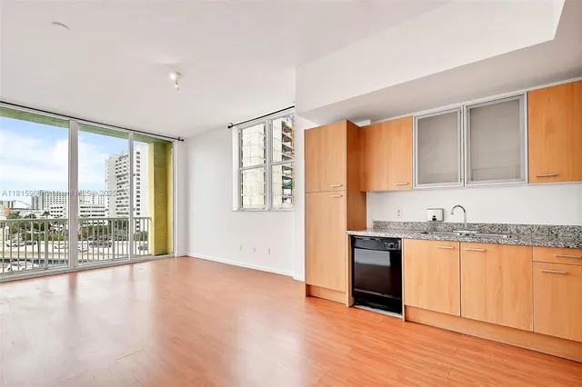 a view of a kitchen with kitchen island wooden floors and stainless steel appliances
